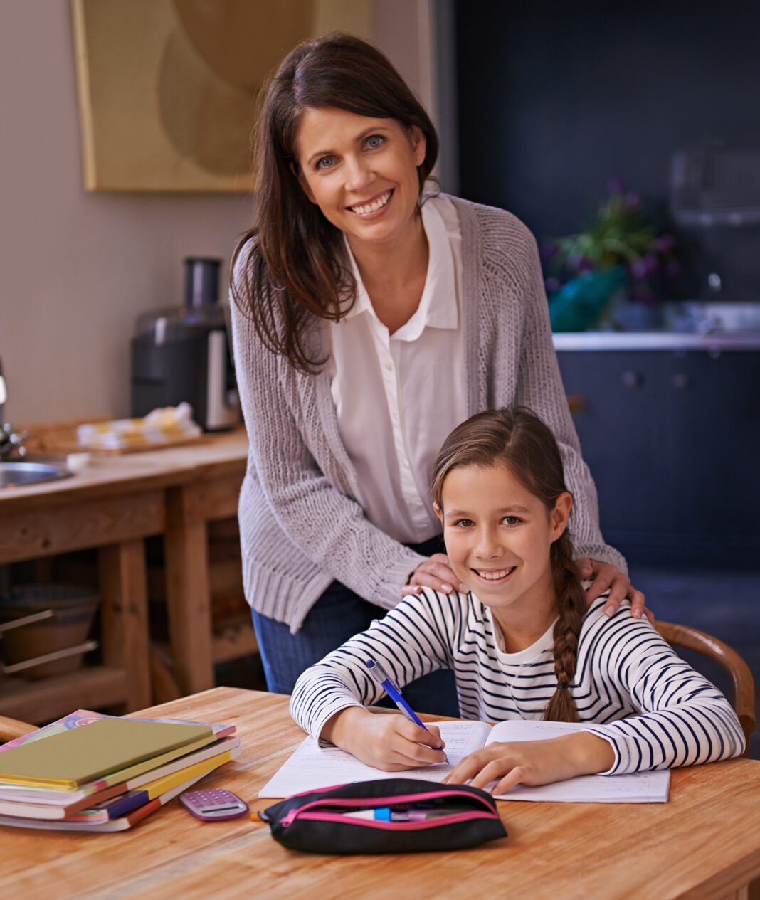 Aide aux devoirs scolaires réussie et complice entre une mère et sa fille à la maison.