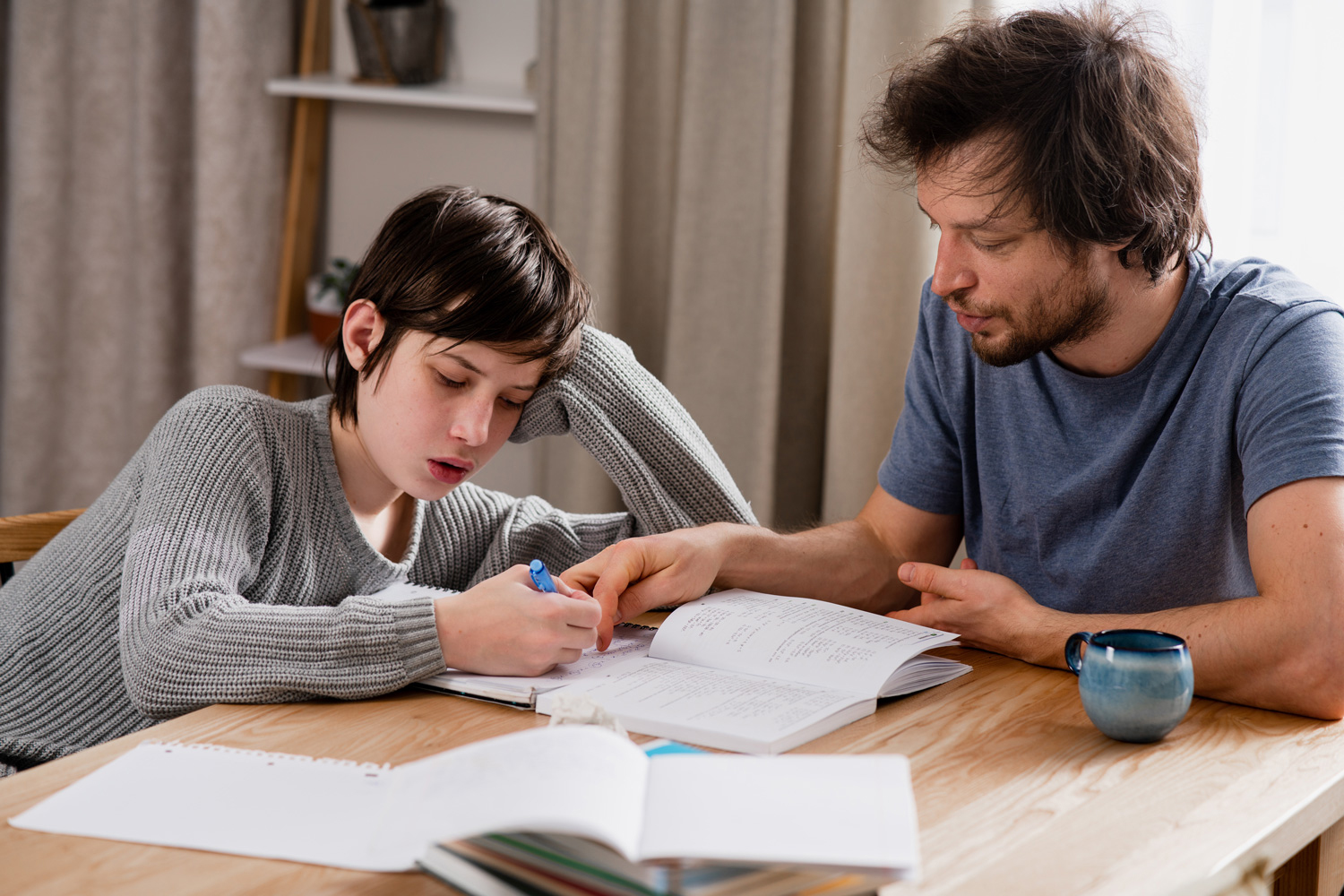 Père ou tuteur aidant un adolescent à faire ses devoirs à la maison