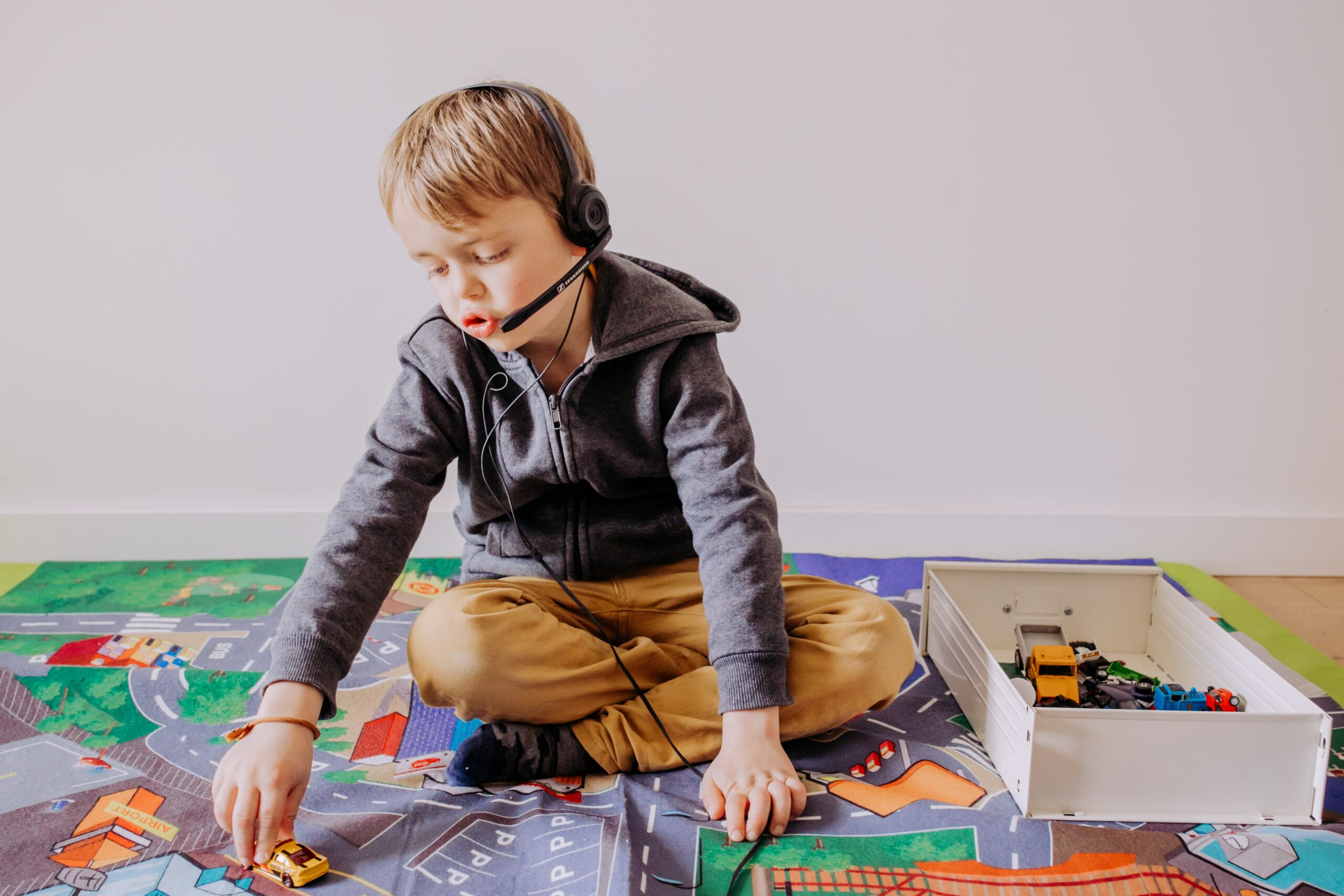 Enfant réalisant un exercice d'écoute de iologo avec micro-casque tout en jouant au sol