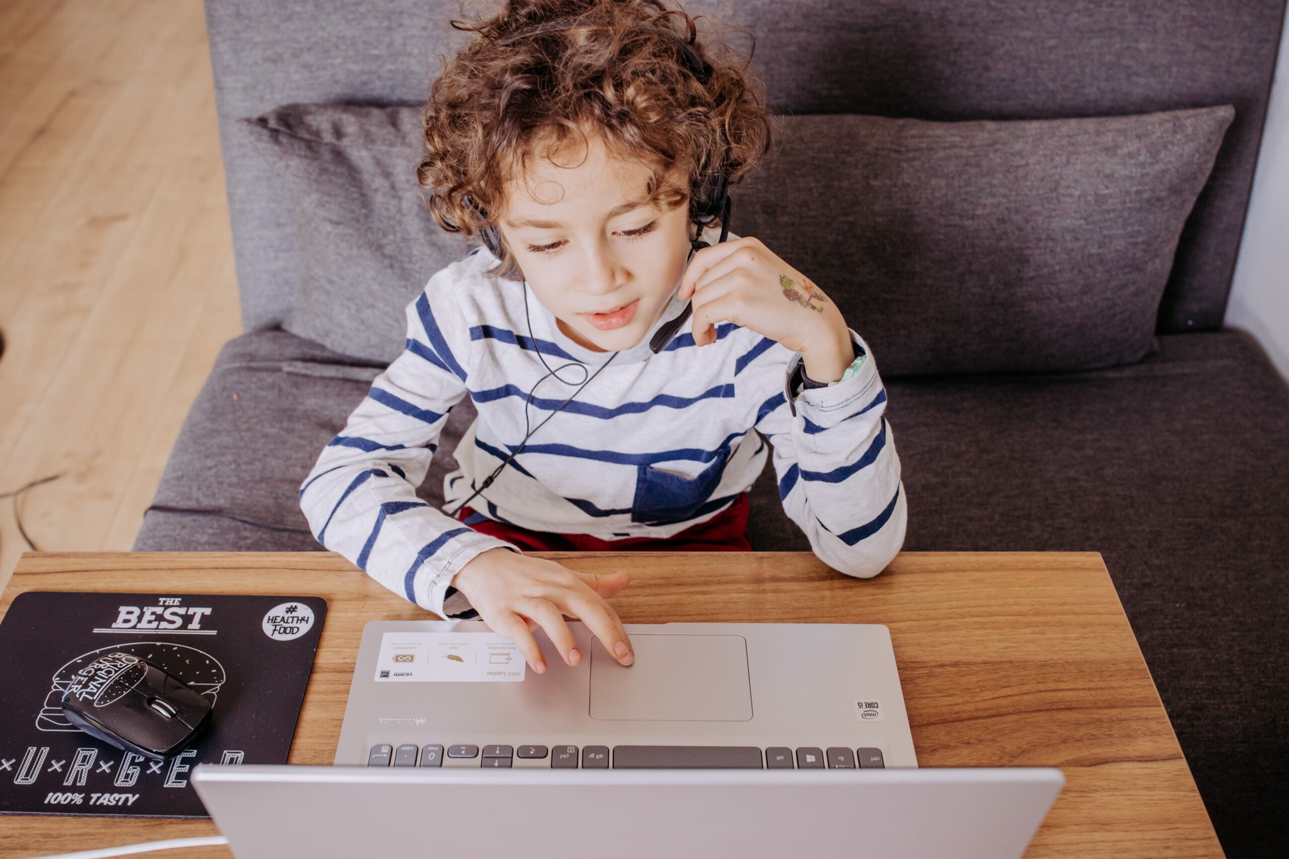 Enfant dyslexique sur ordinateur avec micro-casque utilisant des outils numériques d'orthophonie à la maison